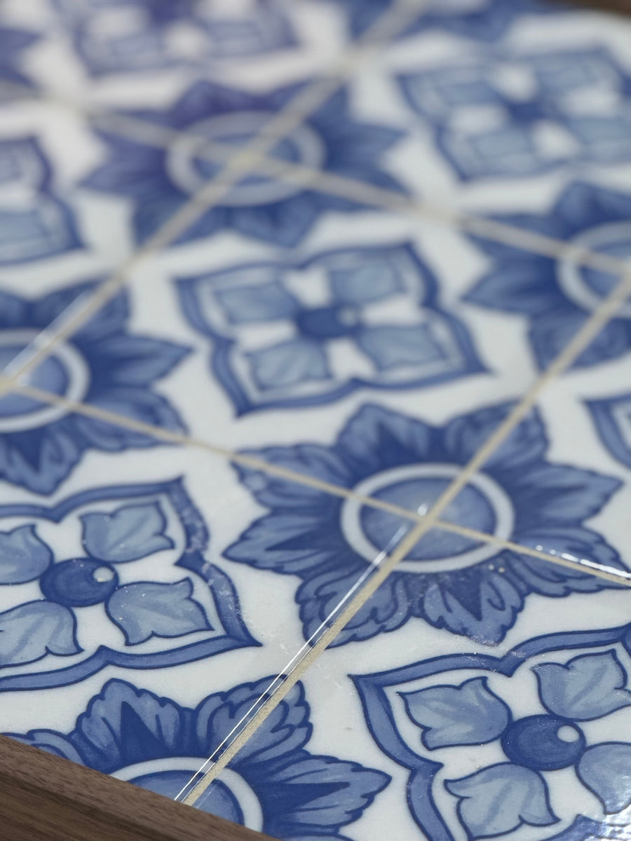 Close-up of patterned blue and white ceramic tiles featuring floral designs and geometric shapes, with visible grout lines.