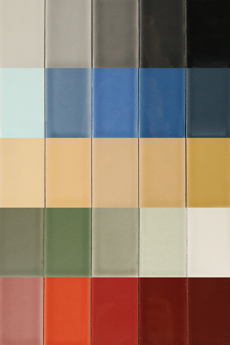 A grid of glossy ceramic tiles, showcasing a variety of colors from gray and blue to earthy tones and vibrant red.