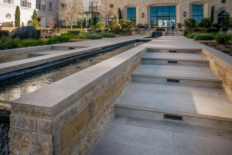 Modern outdoor architectural feature with steps and water feature in a landscaped area.